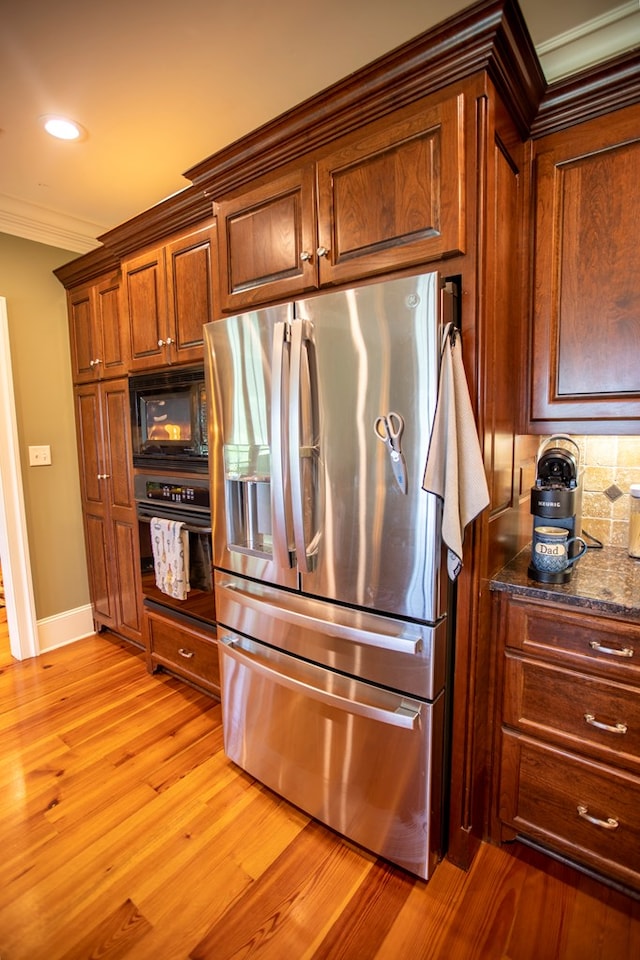 4059 Live Oaks Cir, Valdosta, GA 31601 - kitchen with black appliances, light wood-style floors, crown molding, decorative backsplash, and dark stone counters