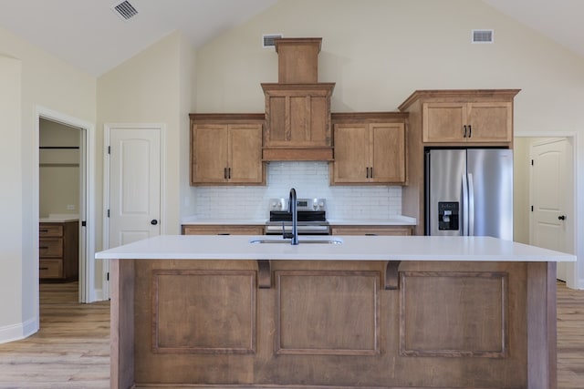 kitchen with appliances with stainless steel finishes, visible vents, a sink, and a center island with sink