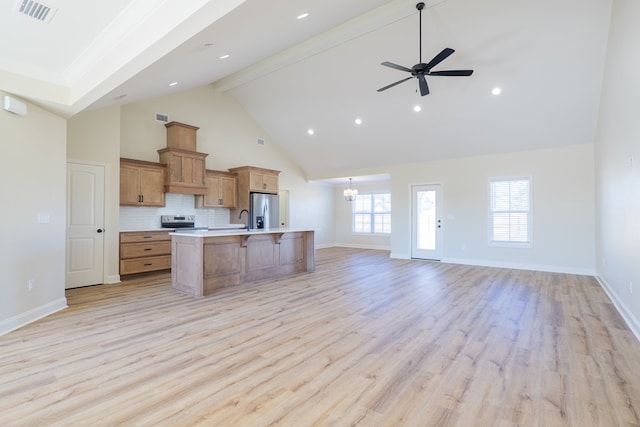 kitchen with stainless steel appliances, visible vents, open floor plan, a kitchen island with sink, and beamed ceiling