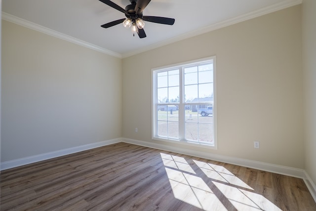 spare room featuring crown molding, wood finished floors, a ceiling fan, and baseboards