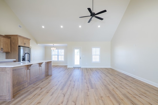 kitchen with stainless steel refrigerator with ice dispenser, visible vents, light countertops, light wood-style floors, and ceiling fan with notable chandelier