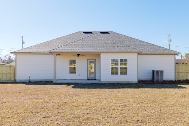 back of house featuring ceiling fan, a shingled roof, fence, and a lawn