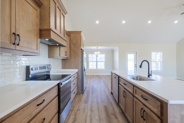 kitchen with light wood finished floors, stainless steel appliances, light countertops, backsplash, and a sink