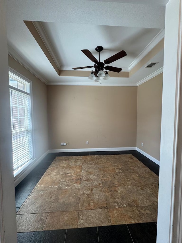 empty room featuring visible vents, a raised ceiling, baseboards, and ornamental molding