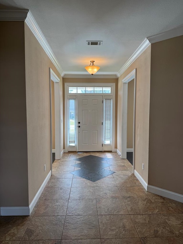 foyer entrance with crown molding, baseboards, visible vents, and stone tile flooring