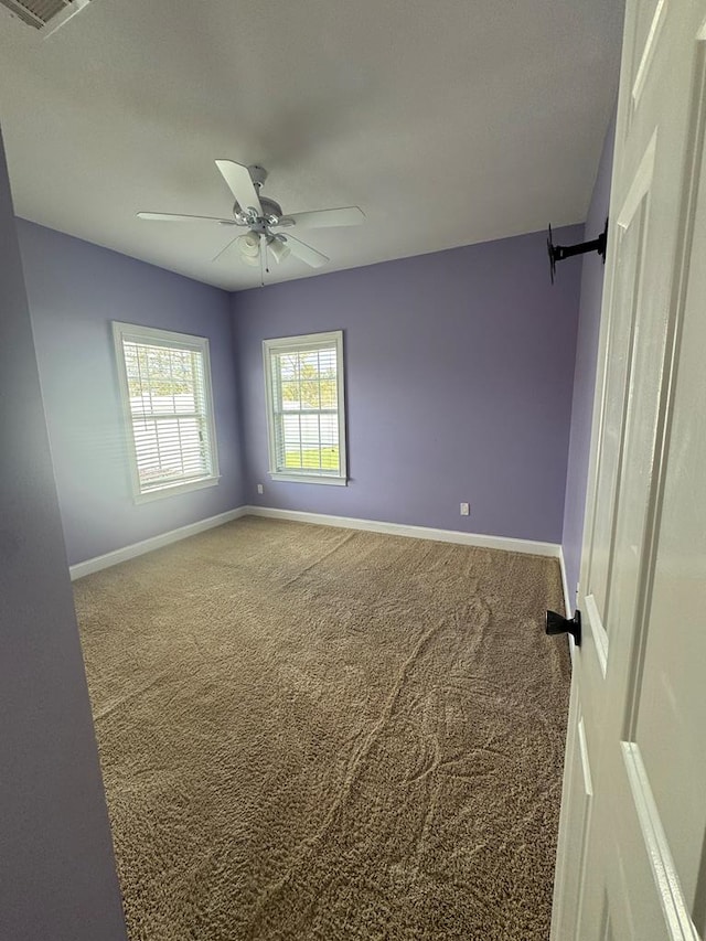 carpeted empty room with baseboards and a ceiling fan