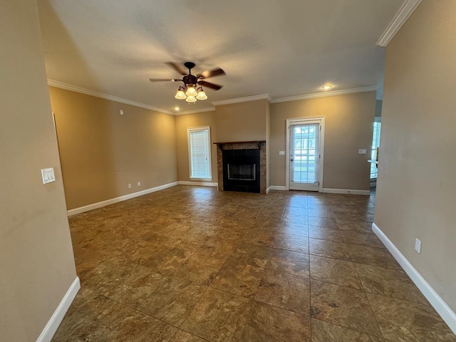 unfurnished living room with a tiled fireplace, crown molding, baseboards, and ceiling fan