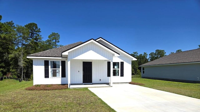 view of front facade with roof with shingles and a front yard