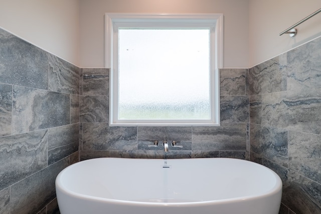 bathroom with a washtub and tile walls