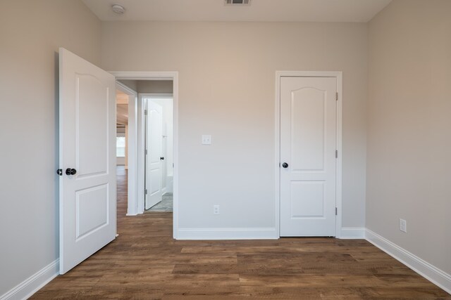 unfurnished bedroom with dark hardwood / wood-style flooring