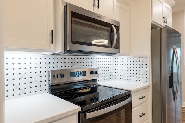 kitchen featuring light stone countertops, tasteful backsplash, crown molding, white cabinets, and appliances with stainless steel finishes