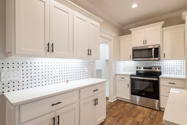 kitchen featuring appliances with stainless steel finishes, tasteful backsplash, ornamental molding, dark hardwood / wood-style floors, and white cabinetry