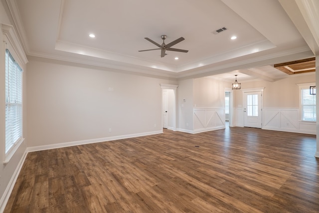 unfurnished living room with a tray ceiling, crown molding, dark hardwood / wood-style flooring, and ceiling fan with notable chandelier