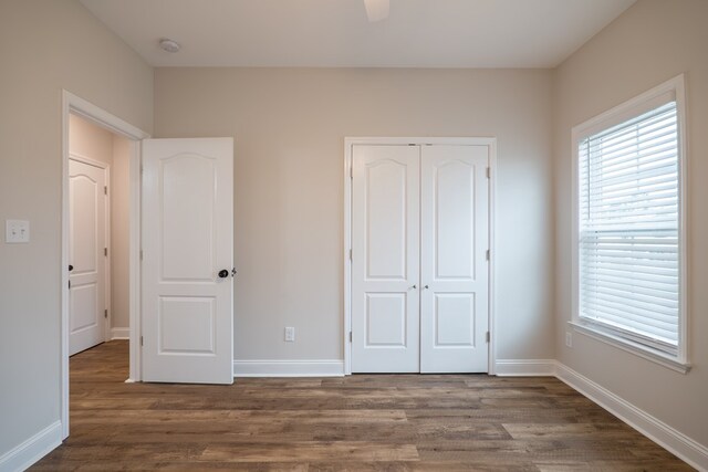 unfurnished bedroom with dark hardwood / wood-style flooring, a closet, and ceiling fan