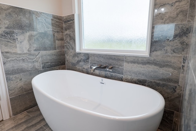 bathroom featuring a bathtub and tile walls