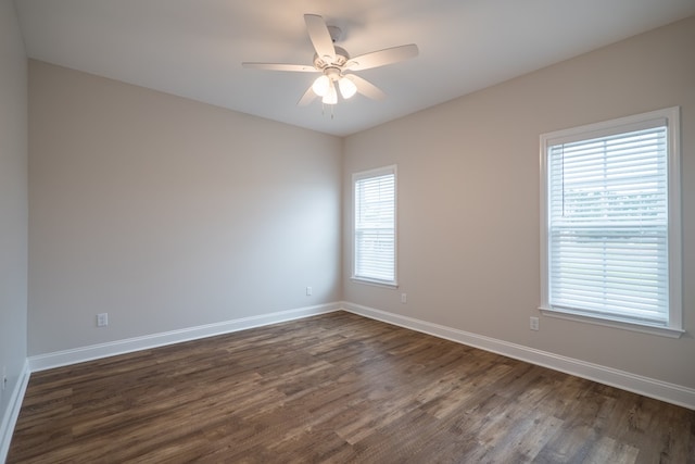 spare room featuring a wealth of natural light, ceiling fan, and dark hardwood / wood-style floors