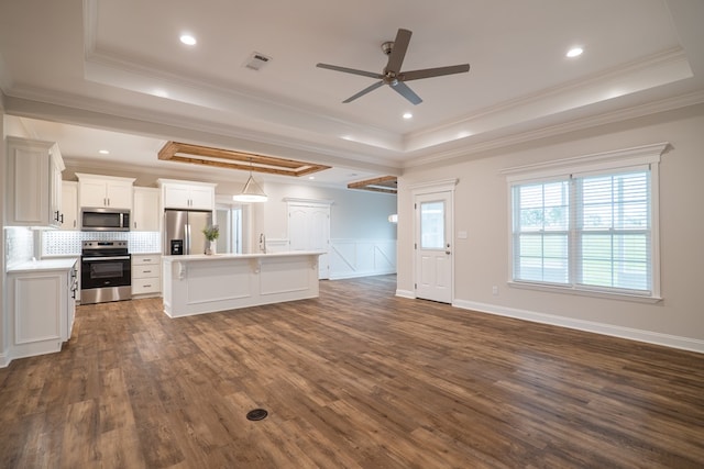 kitchen featuring white cabinets, dark hardwood / wood-style floors, ornamental molding, appliances with stainless steel finishes, and a tray ceiling