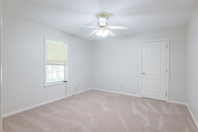 carpeted empty room featuring baseboards, a ceiling fan, and a textured ceiling