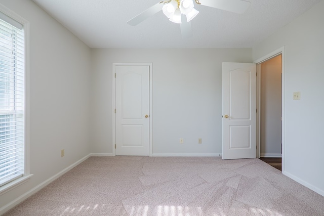 unfurnished bedroom with carpet flooring, multiple windows, and baseboards