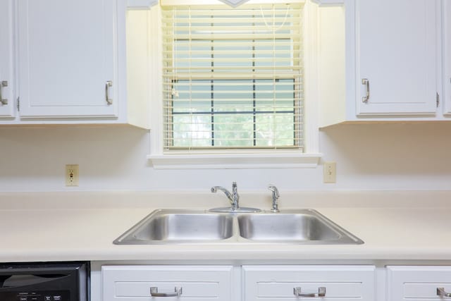 kitchen with dishwasher, light countertops, white cabinets, and a sink