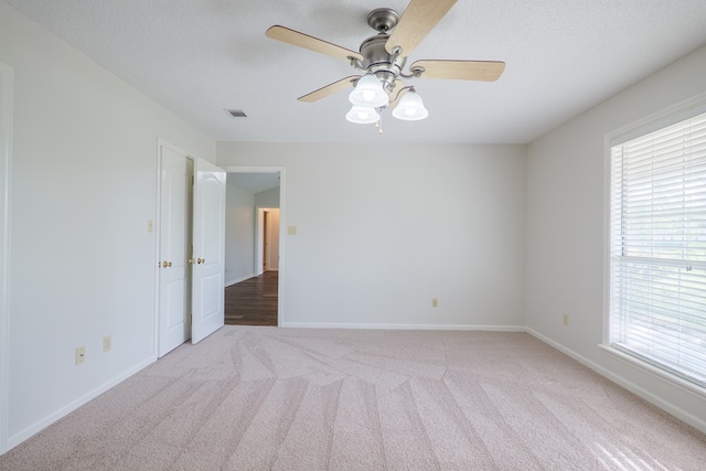 carpeted empty room featuring visible vents, plenty of natural light, and baseboards