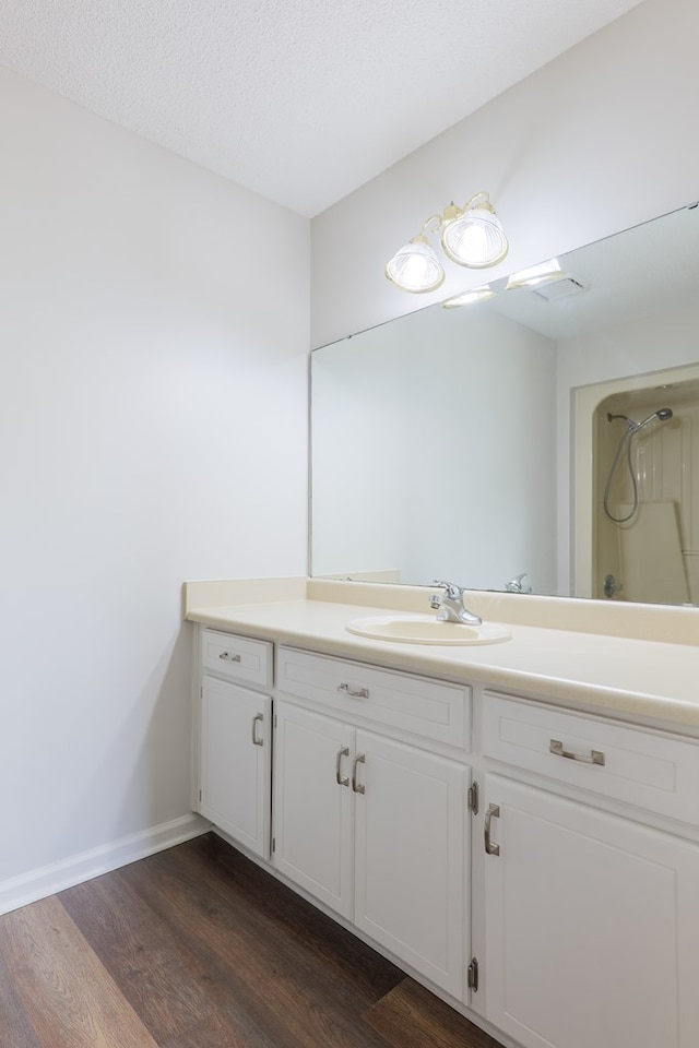 bathroom featuring walk in shower, wood finished floors, vanity, and baseboards