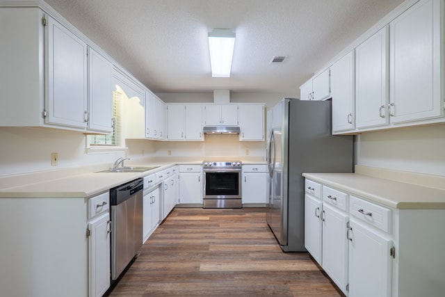 kitchen with a sink, under cabinet range hood, visible vents, a textured ceiling, and appliances with stainless steel finishes