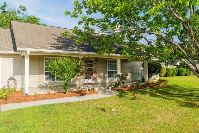 ranch-style house with a front yard, a shingled roof, and covered porch