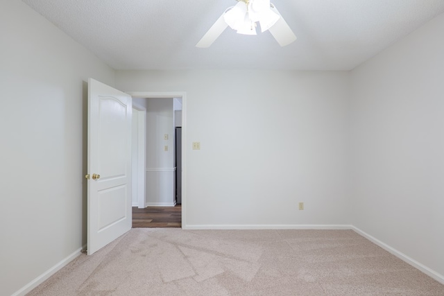 empty room featuring baseboards, a ceiling fan, and carpet
