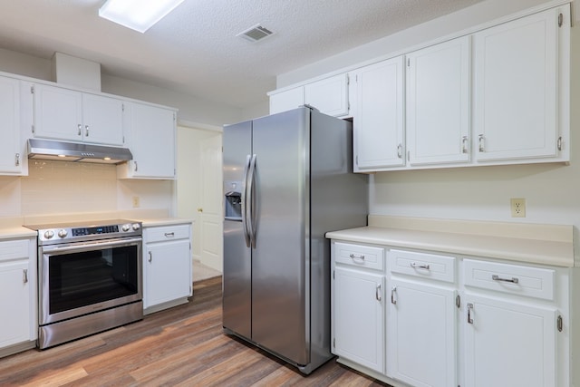 kitchen with stainless steel appliances, under cabinet range hood, visible vents, white cabinetry, and light wood-style flooring