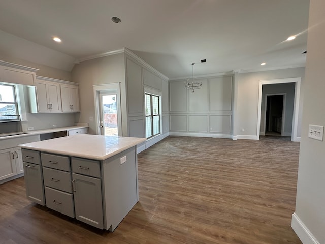 kitchen with hanging light fixtures, hardwood / wood-style flooring, white cabinetry, a kitchen island, and an inviting chandelier