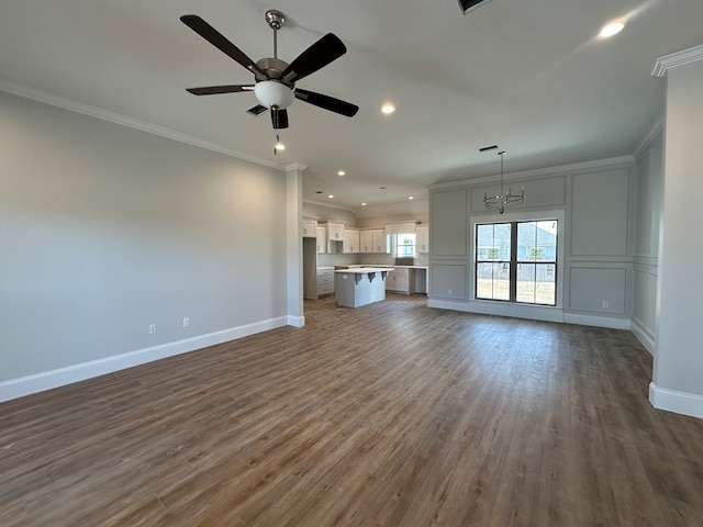 unfurnished living room featuring crown molding, dark wood-type flooring, and ceiling fan with notable chandelier