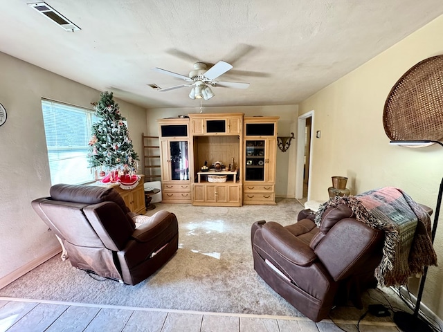 living room with ceiling fan, light carpet, and a textured ceiling