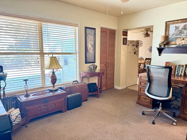 carpeted home office with a textured ceiling and ceiling fan