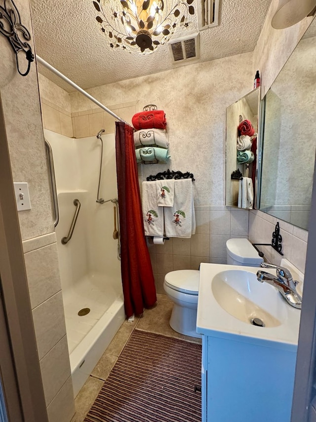 bathroom with tile walls, a shower with shower curtain, vanity, a textured ceiling, and tile patterned floors