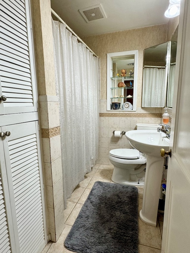 bathroom with tile patterned flooring, tile walls, and toilet