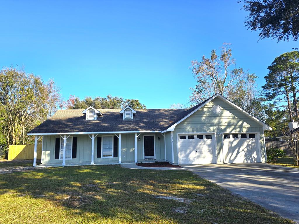 ranch-style house with a porch, a garage, and a front lawn