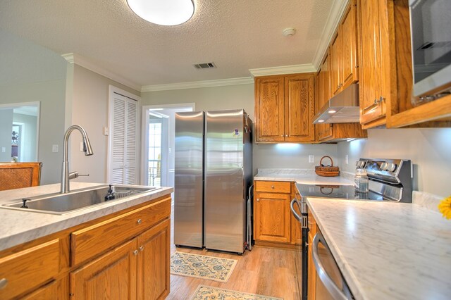 4121 Amberley Trl, Valdosta, GA 31602 - kitchen featuring stainless steel appliances, under cabinet range hood, brown cabinetry, light wood-style floors, and light countertops