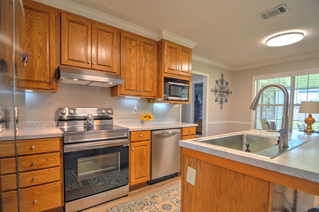 4121 Amberley Trl, Valdosta, GA 31602 - kitchen featuring appliances with stainless steel finishes, under cabinet range hood, light wood-type flooring, brown cabinetry, and ornamental molding
