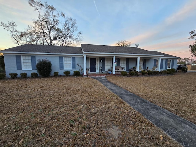 ranch-style house featuring covered porch and a front lawn