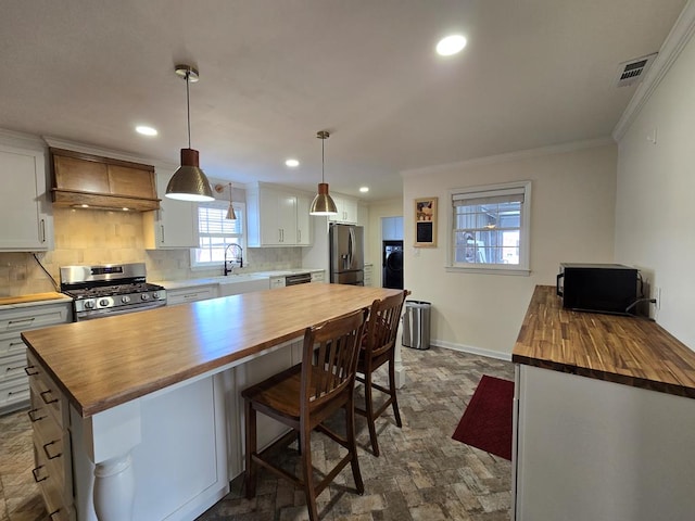 kitchen featuring custom exhaust hood, visible vents, wood counters, and appliances with stainless steel finishes