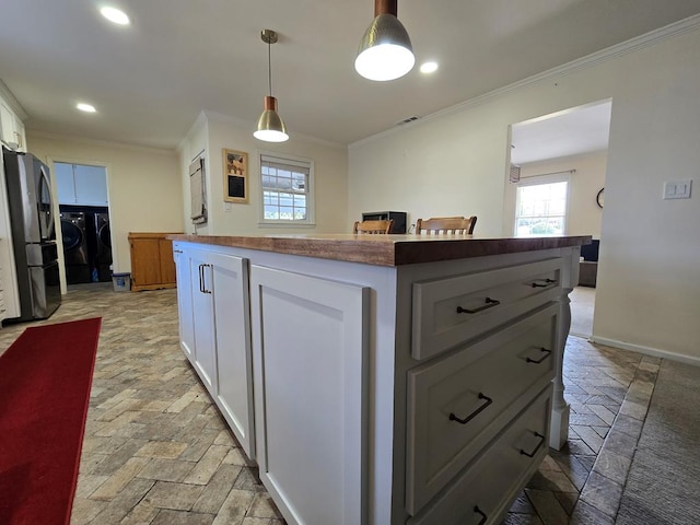 kitchen featuring white cabinets, a kitchen island, ornamental molding, freestanding refrigerator, and independent washer and dryer