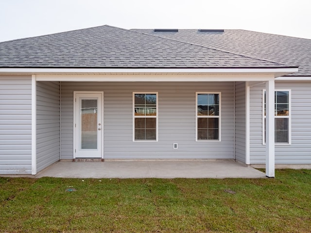 back of house with roof with shingles, a patio, and a yard