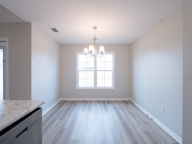 unfurnished dining area with a chandelier, light wood finished floors, and baseboards