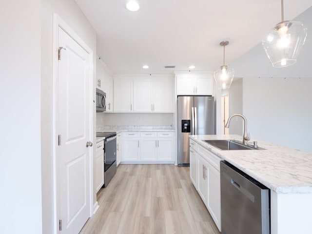 kitchen featuring stainless steel appliances, a sink, light wood-style floors, pendant lighting, and white cabinets