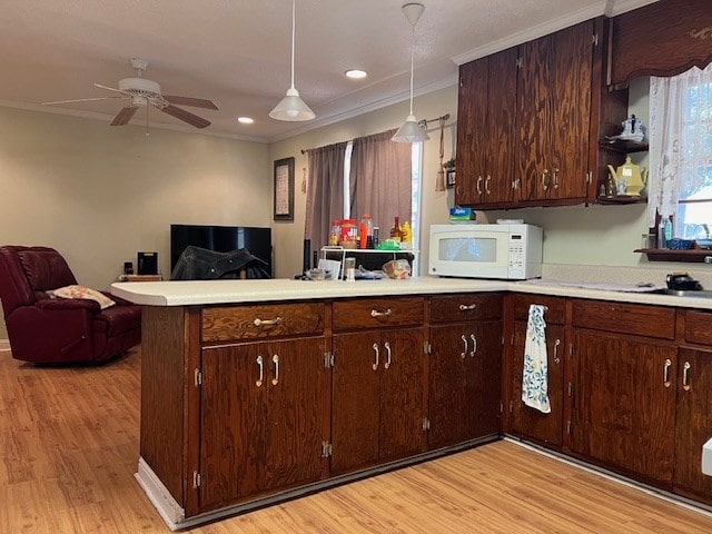 kitchen featuring kitchen peninsula, dark brown cabinets, light hardwood / wood-style flooring, and hanging light fixtures