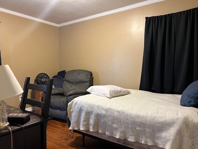 bedroom featuring a textured ceiling, dark hardwood / wood-style flooring, and ornamental molding