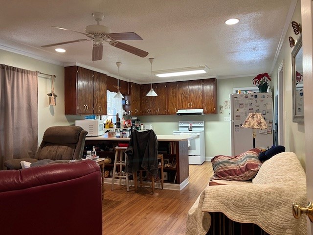 kitchen with light hardwood / wood-style flooring, kitchen peninsula, a textured ceiling, white appliances, and ornamental molding