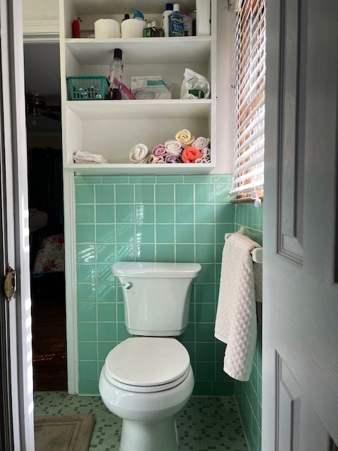 bathroom featuring tile patterned floors, toilet, and tile walls