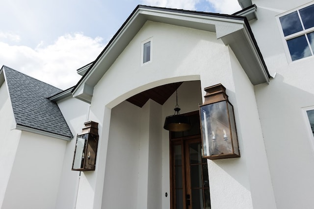 doorway to property featuring a shingled roof and stucco siding